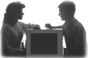 Fotografía mostrando a un hombre frente a una mujer con una computadora de por medio.