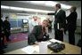 As then-Deputy Assistant Dan Bartlett points to news footage of the World Trade Center, President Bush gathers information about the attack from Emma E. Booker Elementary School in Sarasota, Fla., Sept. 11, 2001. White House photo by Eric Draper