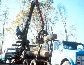 Knuckle boom unloading logs from log truck