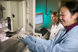 Technician loads fungal endophyte samples into a genetic analyzer while mycologist examines the raw DNA sequence data: Click here for full photo caption.