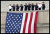 A Marine Band trumpeter plays Taps while first responders and officials salute a flag that hangs on the side of the Pentagon Thursday, Sept. 11, 2008, during the dedication of the 9/11 Pentagon Memorial at the Pentagon in Arlington, Va.