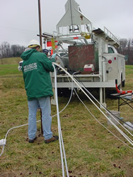 USGS scientist guiding the BAT3's tubing down a borehole at the Lake Wheeler Road Research Site, NC. A hoist truck used to lower the BAT3 is in the background