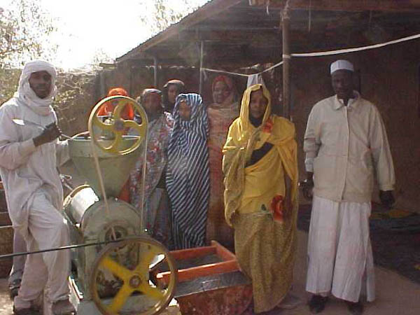 Members of a women's association in Massaguet look on as peanuts are ground and pressed into cooking oil