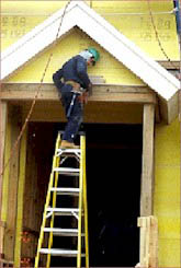 Worker improperly standing on the top rung of a stepladder working on a doorway of a building