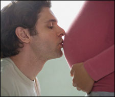 Photo: A man kissing the belly of a pregnant woman