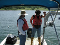 USGS scientists on a boat are collecting sediments from the bottom of the Camp Far West Reservoir, California. Samples are collected in Teflon® core tubes for benthic-flux analysis. A davit and winch used for core sampling is on the right. A davit is a small crane on ships that raises and lowers objects over the side.