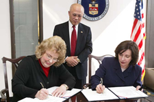 Image of two women signing papers and the departments CFO