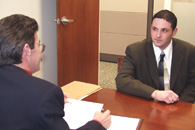 A DS investigator, left, interviews a job candidate, right.