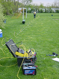  [Photo: USGS scientist wearing GPS backpack walks along cable.] 