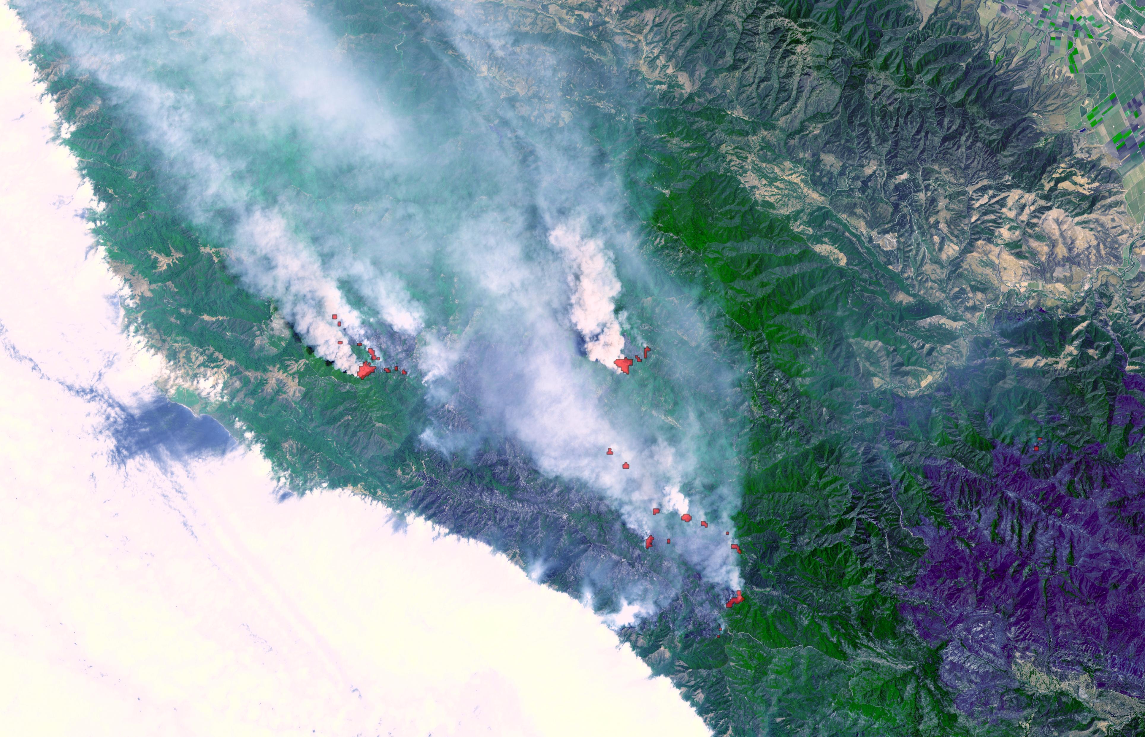 Big Sur fire, June 29, 2008. The satellite image combines a natural color portrayal of the landscape, with thermal infrared data showing the active burning areas in red. The dark area in the lower right is a previous forest fire.