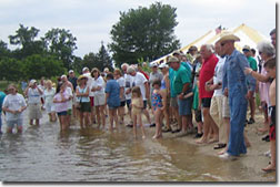 Maryland Senator Bernie Fowler leading a crowd down the bank of a waterbody.