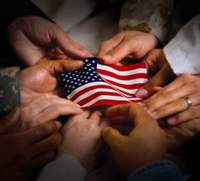 numerous hands holding an American flag 