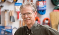 Man standing with hardware products on wall behind him