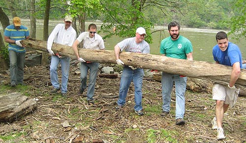 Photo of staff cleaning up C&O Canal Park carrying a large log