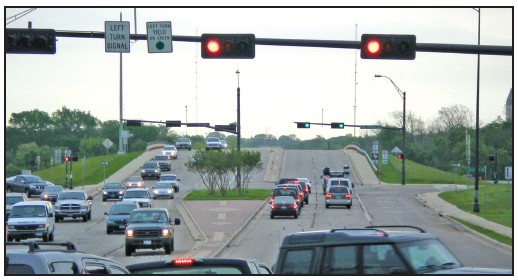 Photo of signalized intersection with one way only and right turn only signs mounted to the mast arm.