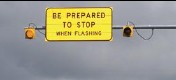 Photo showing a sign advising drivers to prepare to stop ahead when the attached warning lights are flashing.