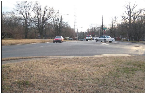 Photograph shows a busy T intersection in advance of a signalized intersection.