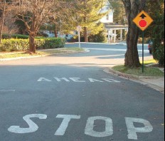 Photograph of pavement marking advising drivers of a STOP sign ahead.