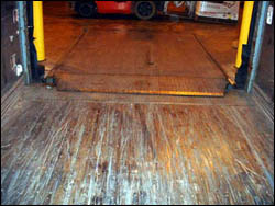 Manual dock plate is secured into position. Always walk and inspect trailer floor before boarding.