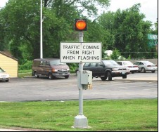 Photo of a sign that warns drivers that traffic is entering the roadway from the right when the attached light is flashing.