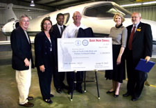 Officials in airport hanger posing with EDA investment check. Click here for larger image.