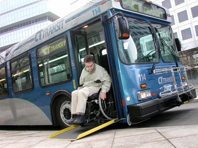 Rider manuevering wheelchair off of low-floor bus utilizing ramp.