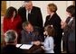 After signing a proclamation recognizing October as Domestic Violence Month, President George W. Bush shakes hands with Monique Blais, 7, the young artist who designed the Stop the Violence postage stamp in the East Room Wednesday, Oct. 8, 2003.  White House photo by Tina Hager