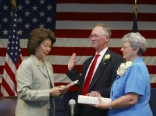 Secretary of Labor Elaine L. Chao (L) administers the oath of office to W. Roy Grizzard, Jr., (C) as his wife Nancy (R) looks on.