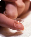 A woman holding a contact lens on her index finger.