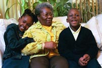 A grandmother and her two grandchildren enjoy a hug in their living room.