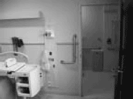 Photograph of patient room, St. Joseph Hospital. Patient bathrooms are near bed. Note the hand rail.