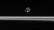 The Cassini spacecraft looks across the unlit ringplane as Mimas glides 
silently in front of Dione