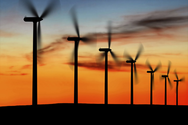 A row of wind turbines at sunset.