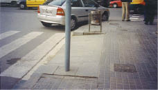 Case Study: Two contrasting photos show a US intersection with space-consuming flared curb ramps compared with an intersection in Barcelona, Spain, where the sides of the ramps are shielded from pedestrian travel by poles or trash cans, leaving more sidewalk area for pedestrians.