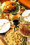 A dinner table with a turkey, stuffing, pie,wine and plates