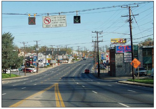 Photograph of a downtown area with posted variable lane use signs that indicate when restrictions on making left turns from a continuous center turn lane are in place.