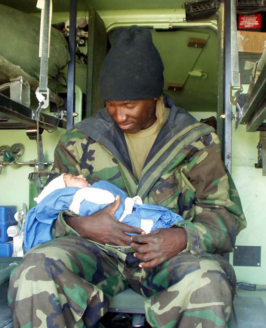 Chief Hospital Corpsman of a Marine Expeditionary Unit holds a two-hour-old newborn in Nasiriyah, Iraq, April 3, 2003. 