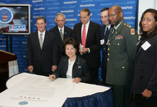 Sec. Chao seated in front of Charles Ciccolella, Craig Duehring, former U.S. Sen. Bob Dole, Capt. Shane Doucet, Lt. Col. Michael Hague, and Arsenia Edwards.