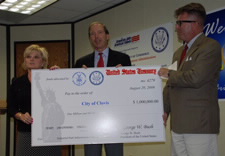 Mayor of Clovis, Gayla Brumfield,  U.S. Representative Tom Udall and Deputy Assistant Secretary for External Affairs and Communications Matthew Crow pose with presentation image of $1million check. Click for larger image.