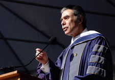 Gutierrez in academic robe adressing students and faculty on podium.
