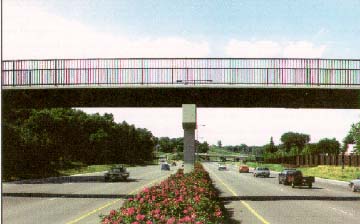 photo: six lane highway divided by a median with flowers, spanned by a bridge