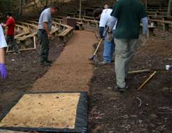 Photo of volunteers smoothing the surface layer of treated engineered wood fiber