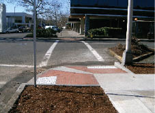 Case Study: Photo of new paired red brick curb ramps installed at a corner with a tight radius. See discussion for details.