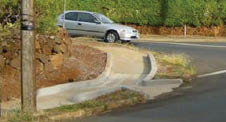 Case Study: Two photos from different angles of curb ramps added to a sidewalk that curves down around a corner in an existing hilly residential neighborhood.