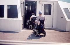 people using power chairs board vessel