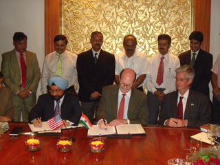 RIL Senior Vice President Prem Sawhney (seated far left) and Deputy Chief of Mission Steven White (seated center) sign the USTDA grant agreement that will fund investment analysis for RIL on a proposed coal-to-liquids project, while USTDA Country Representative Bala Kalyanaraman (standing third from left) looks on.