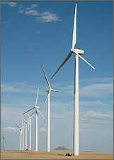 Photo of a row of eight, large three-bladed, wind turbines on a sunny day.