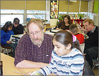 Photo of an NREL CLOUT tutor helping a student read about science.