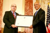 USCIS Director Emilio T. González presents M.J. Khan with the “Outstanding American by Choice” recognition in Washington, DC, Apr. 23, 2007