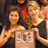 Two female members of the Pittsburgh Opera holding a copy of the concert program